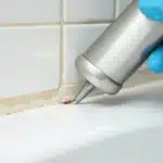 Contractor applying caulking to a bathtub.
