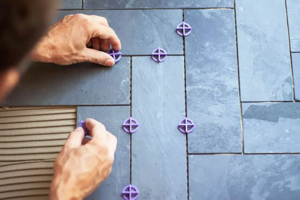 Contractor installing tiles on wall.