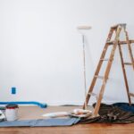 Room prepared for interior painting with ladder, paint cans, and drop cloth