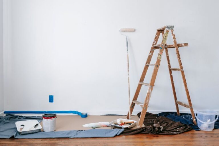 Room prepared for interior painting with ladder, paint cans, and drop cloth