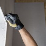Close-up of a gloved hand applying plaster to a wall indoors in Falun, Sweden.