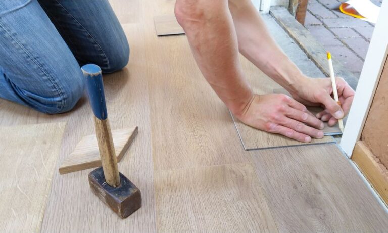 Craftsman measuring wood floor panels for installation