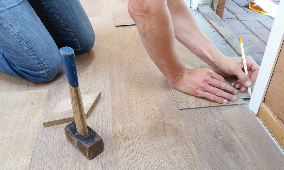 Craftsman measuring wood floor panels for installation